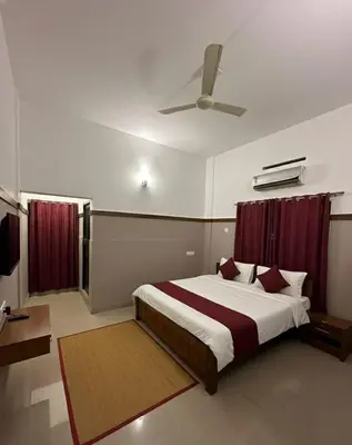 a bedroom with a large bed with red curtains at The Rosetta Inn, Wayanad in Wayanad