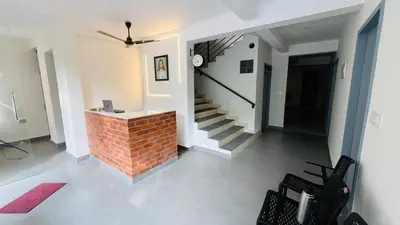 a living room with a brick fireplace and a staircase at Jo Homes in Alwaye
