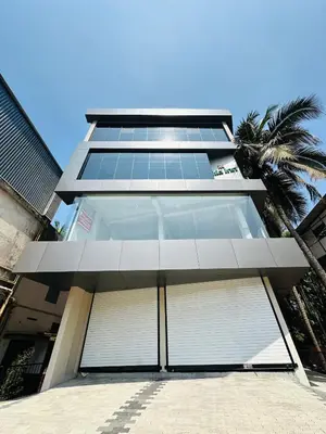 a building with two garage doors and a palm tree at Nila Inn Calicut Near Hilite Mall in Kozhikode