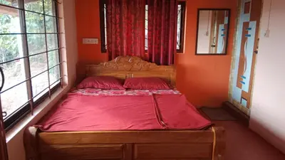 a bed in a room with orange walls and windows at Danny's Homestay Coorg in Madikeri