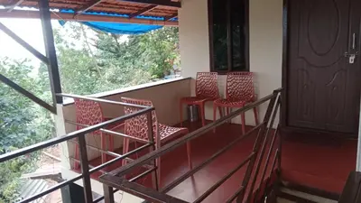 a balcony with red chairs and a window at Danny's Homestay Coorg in Madikeri