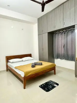 a bedroom with a bed with a wooden headboard at Dakshima Residency in Mysore