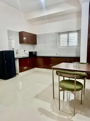 a kitchen with a table and a chair in it at Dakshima Residency in Mysore