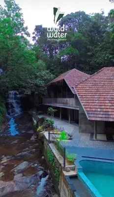 a resort with a pool and a river at WyldWater Retreat in Vythiri
