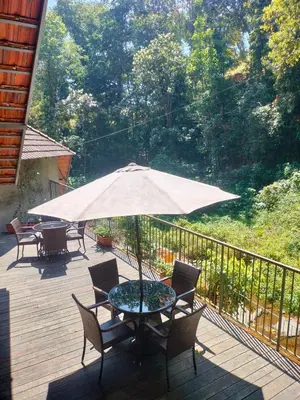 a table and chairs with an umbrella on a deck at WyldWater Retreat in Vythiri