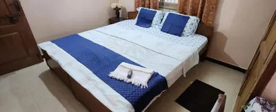 a bed with blue and white sheets and blue pillows at Deepam Homestay in Coimbatore