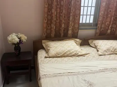 a bedroom with a bed and a vase of flowers on a table at Deepam Homestay in Coimbatore