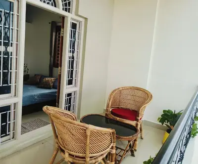 a balcony with two chairs and a table and a couch at Āsare attic in Mysore