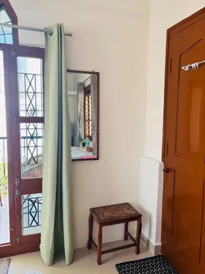 a room with a mirror and a stool next to a door at Āsare attic in Mysore