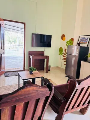 a living room with two wooden chairs and a table at Aasare Attic 2 in Mysore