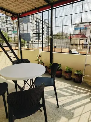 a table and chairs in a room with windows at Aasare Attic 2 in Mysore