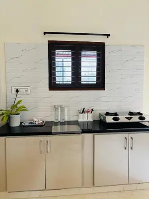 a kitchen with a black counter top and white tiles at Aasare Attic 2 in Mysore
