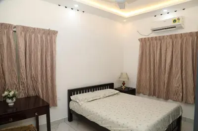 a bedroom with a bed and a desk and curtains at Brand new 4 BHK luxury villa near kochi airport in Nedumbassery