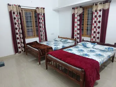 two beds in a room with windows at SoNish Homestay Marayur - 3 bedroom for 25-30 people - Booking will be confirmed only after advance payment in Marayoor