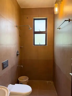a bathroom with a shower and a toilet and a window at Homestay in Alappura 3 Cottage Farmstay by Homeyhuts in Tattamangalam