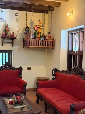 a living room with two red couches and a shelf with toys at Homestay in Alappura 3 Cottage Farmstay by Homeyhuts in Tattamangalam