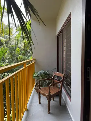 a wooden bench sitting on a balcony with a window at Homestay in Alappura 3 Cottage Farmstay by Homeyhuts in Tattamangalam