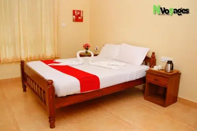 a bedroom with a large bed with a red and white blanket at Nvoyages Wayanad in Wayanad