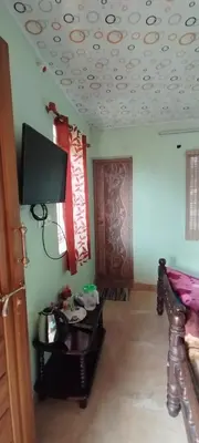a room with a bed and a tv on the wall at Yakuhomestay in Vālpārai