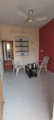 a living room with two white chairs and a table at Yakuhomestay in Vālpārai