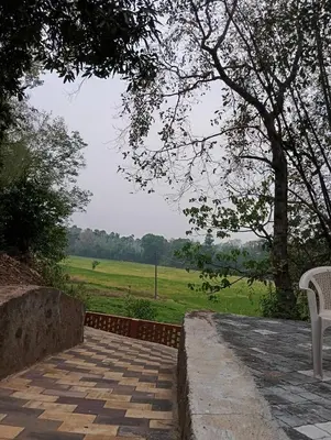 a walkway with two white chairs and a field at The Cool Ranch at gaya3farms in Parli
