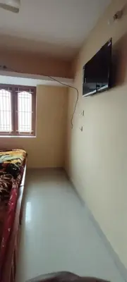 a room with a bed and a tv on a wall at sarathihomestay in Vālpārai
