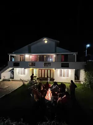a group of people sitting outside of a building at night at Hill Side Cottage in Ooty
