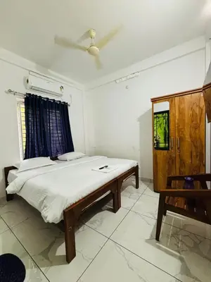a bedroom with a bed and a table in it at MIRACLE INN Rajagiri in Cochin