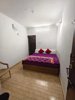a bedroom with a bed with two red pillows at MISTY cottage in Ooty