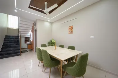 a dining room with a table and green chairs at 4-Bedroom Villa near CIAL Airport 25 Min Drive ! in Alwaye