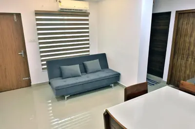 a living room with a blue couch and a table at Vaiga Heavens , 1 BHK Apartment in Guruvāyūr