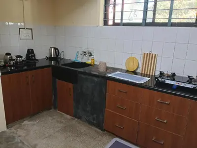 a kitchen with a black counter top and wooden cabinets at Formula 1 Premium Villa in Mysore
