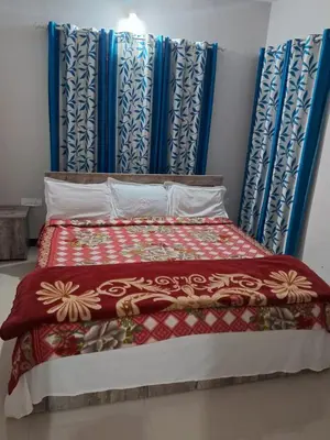 a bed with a red blanket and blue curtains at Grays club guest House in Coonoor