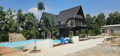 a house with a swimming pool in front of it at Ambience Retreat in Malavalli