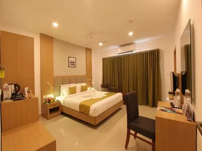 a hotel room with a bed and a desk and a chair at Hotel Salkara Chavakkad in Manattala