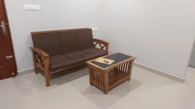 a brown couch and a table in a room at Lavender airport suite in Angamali