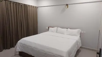 a bedroom with a large white bed with curtains at Lavender airport suite in Angamali
