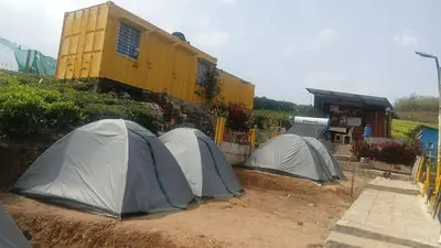 a group of tents in the dirt near a train at Janardan Campsite Ooty in Ooty