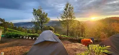 a tent in a field with the sunset in the background at Janardan Campsite Ooty in Ooty
