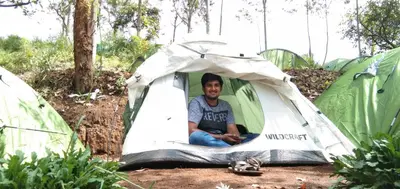 a man sitting inside of a tent at Oak and Sky Adventures, Kanthalloor in Kanthalloor
