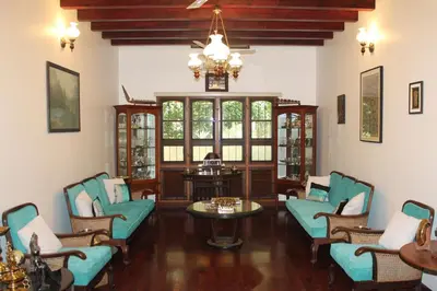 a living room with chairs and a table and a chandelier at Heritage Home Near Cochin Airport in 5-Acre Farm in Angamali