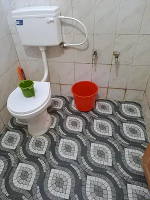 a bathroom with a toilet and buckets on a mosaic floor at Kunjoose Ladies Hostel in Trichūr