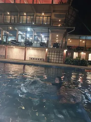 a person swimming in a swimming pool at night at Paarpidam in Tānūr