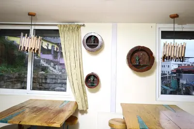 a dining room with a wooden table and two windows at Valparai home villas in Vālpārai