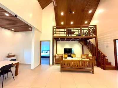 a living room with a spiral staircase and a dining room at Evara Stays Coorg in Kushālnagar