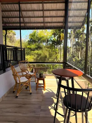 a porch with chairs and a table and a table and chairs at Evara Stays Coorg in Kushālnagar