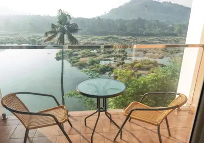 a table and two chairs on a balcony with a view at River Bay Athirappilly in Athirappilly