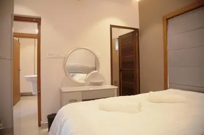 a bedroom with a white bed and a mirror at Gentur Enclave in Mananthavady