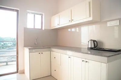 a kitchen with white cabinets and a sink and a window at Gentur Enclave in Mananthavady