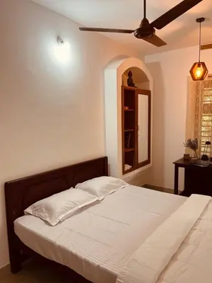 a bed in a bedroom with a ceiling fan at Mathangi - A Countryside Homestay for Family and Solo Travelers in Kozhikode
